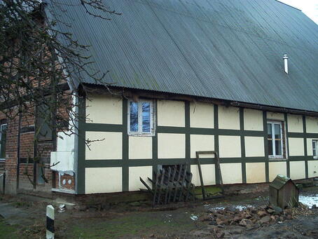 Uenzen, Hofstelle, Styropordämmung mit aufgemalten Fachwerkständern und -riegeln an der Nordseite (2002), Die beiden ursprünglichen Luchtfenster sowie der untere Teil der Türöffnung wurden zugemauert. Im oberen Teil wurde ein Fenster für das nachträglich in die Lucht eingebaute Zimmer eingesetzt. © Interessengemeinschaft Bauernhaus, Jenny Heinrichsdorff-Struß und Herbert Struß